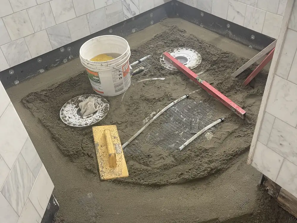 Mortar bed being floated by hand over wire lath and radiant tubing