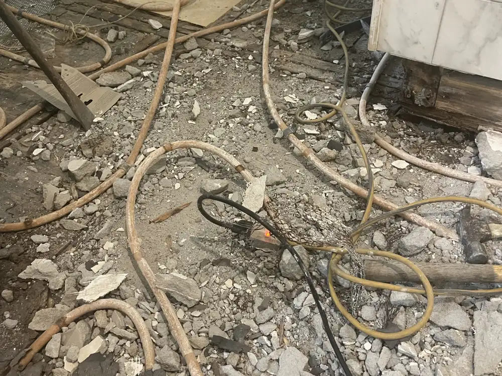 Failed shower floor torn out down to the joists, old mortar bed and radiant tubing exposed